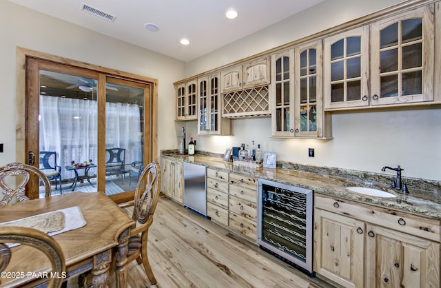 kitchen with wine cooler, light brown cabinetry, sink, refrigerator, and light stone counters