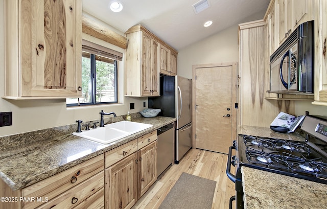 kitchen with vaulted ceiling, light hardwood / wood-style floors, sink, appliances with stainless steel finishes, and light brown cabinetry