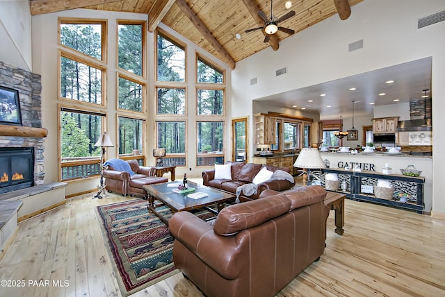 living room with beamed ceiling, light hardwood / wood-style floors, a fireplace, and high vaulted ceiling