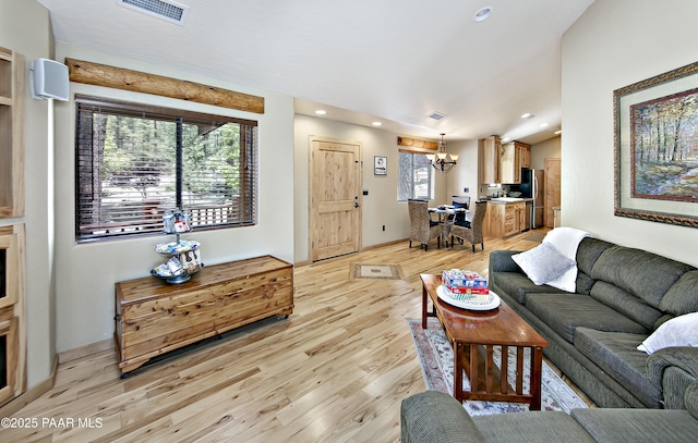 living room with a wealth of natural light, light wood-type flooring, and an inviting chandelier