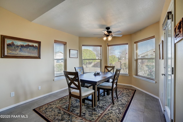 dining space featuring tile patterned flooring, ceiling fan, a textured ceiling, and baseboards