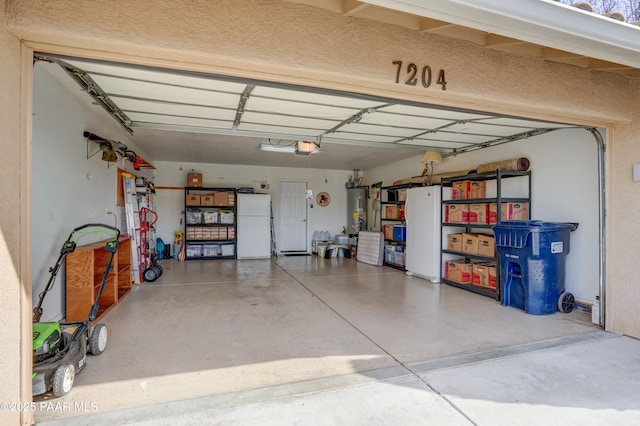 garage featuring water heater, freestanding refrigerator, and a garage door opener