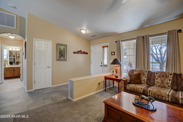 living area featuring lofted ceiling, carpet, visible vents, and arched walkways