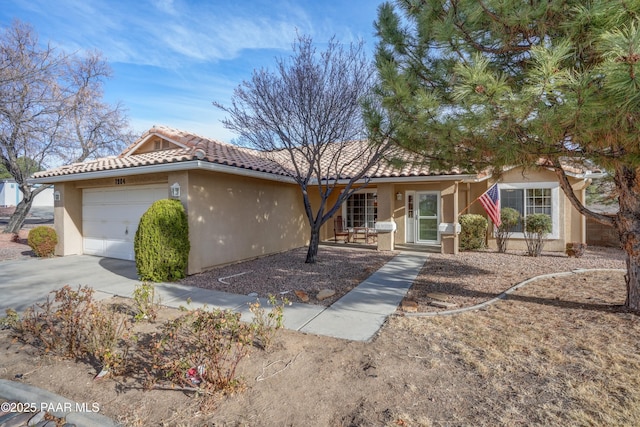 ranch-style house with a garage, driveway, a tile roof, and stucco siding