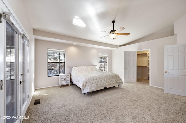 bedroom featuring a spacious closet, carpet floors, ceiling fan, and vaulted ceiling