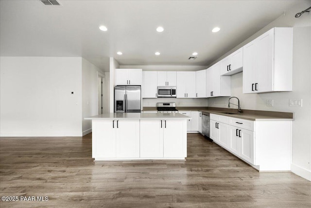 kitchen with white cabinets, a kitchen island, sink, and appliances with stainless steel finishes