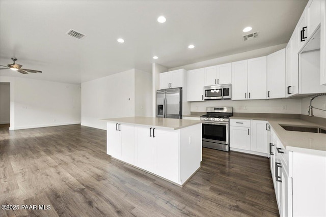 kitchen with white cabinetry, a center island, stainless steel appliances, and sink