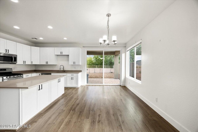 kitchen featuring sink, an inviting chandelier, pendant lighting, white cabinets, and appliances with stainless steel finishes