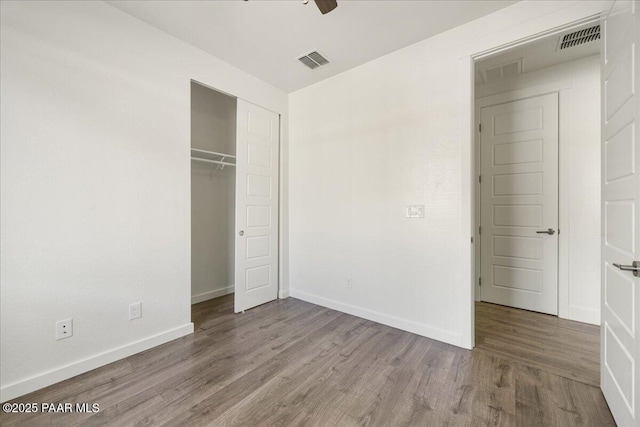 unfurnished bedroom featuring a closet, hardwood / wood-style floors, and ceiling fan