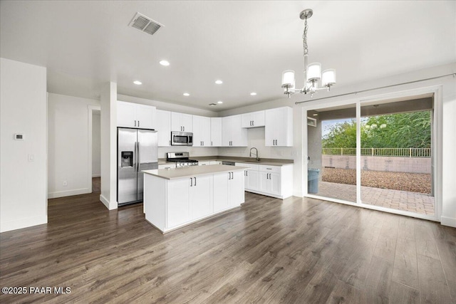 kitchen featuring a center island, dark hardwood / wood-style floors, decorative light fixtures, white cabinetry, and stainless steel appliances