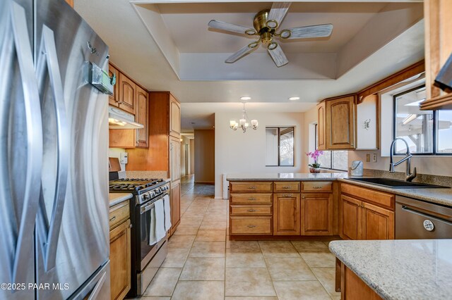 1086 N Broken Wagon Trl, Dewey-Humboldt, AZ 86327 - kitchen with stainless steel appliances, under cabinet range hood, a raised ceiling, a chandelier, and brown cabinetry