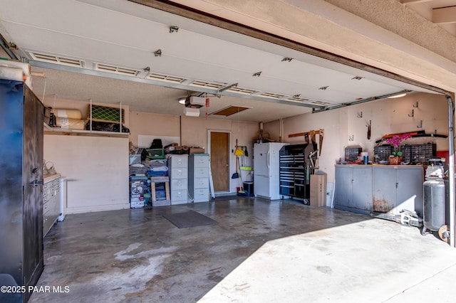 1086 N Broken Wagon Trl, Dewey-Humboldt, AZ 86327 - garage featuring freestanding refrigerator, a garage door opener, and a workshop area