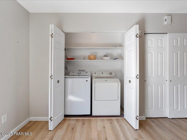 laundry room featuring washing machine and dryer, light wood finished floors, and baseboards