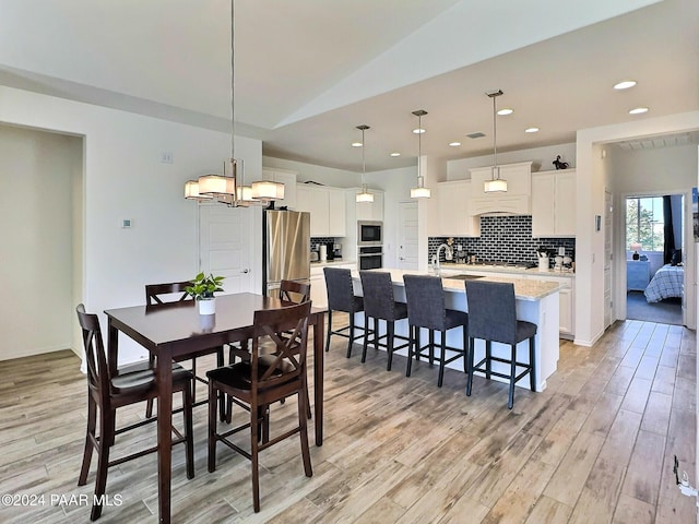 dining space with light hardwood / wood-style floors and vaulted ceiling