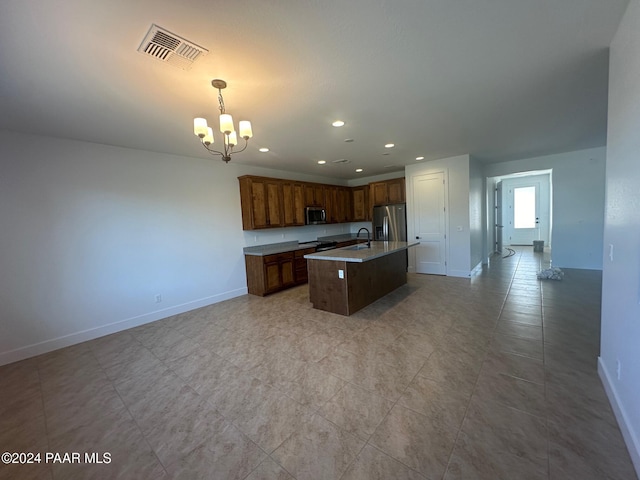 kitchen featuring sink, hanging light fixtures, stainless steel appliances, an island with sink, and a chandelier