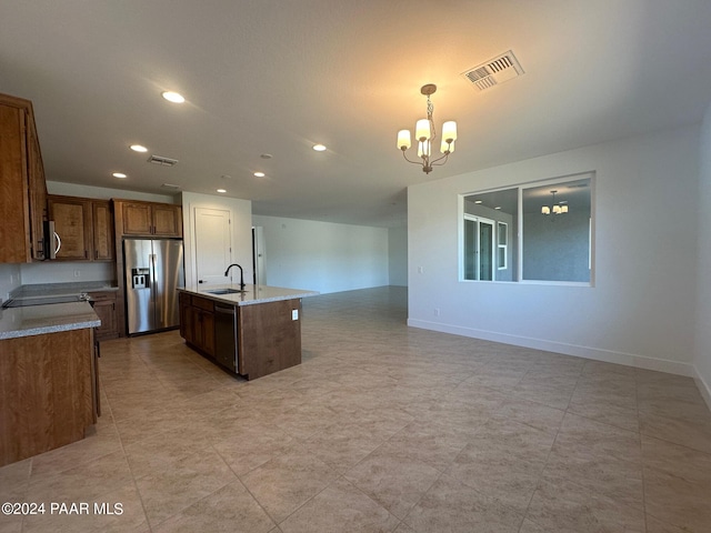 kitchen with stainless steel appliances, a kitchen island with sink, sink, decorative light fixtures, and a chandelier