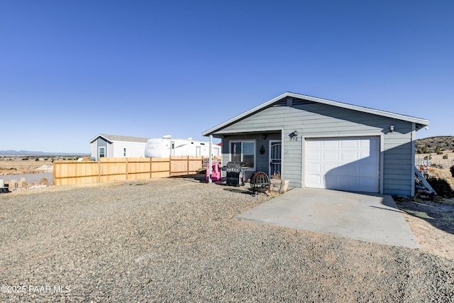 view of front of property with driveway, an attached garage, and fence