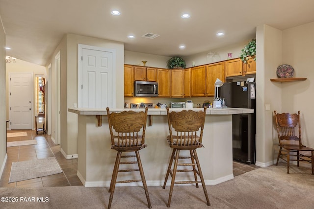 1222 Crown Ridge Dr, Prescott, AZ 86301 - kitchen with stainless steel microwave, recessed lighting, light countertops, a kitchen breakfast bar, and brown cabinetry