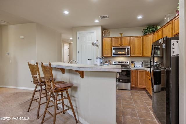 1222 Crown Ridge Dr, Prescott, AZ 86301 - kitchen with stainless steel appliances, a kitchen bar, recessed lighting, tile countertops, and brown cabinetry