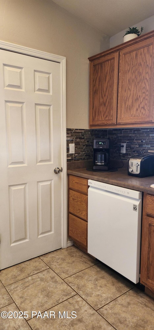 1125 N Wagon Wheel Pl, Chino Valley, AZ 86323 - kitchen featuring white dishwasher, dark countertops, tasteful backsplash, and brown cabinetry