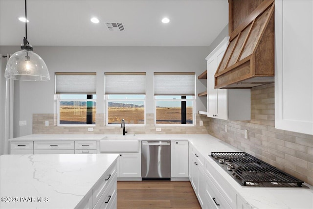 kitchen with white cabinetry, sink, hanging light fixtures, stainless steel appliances, and premium range hood