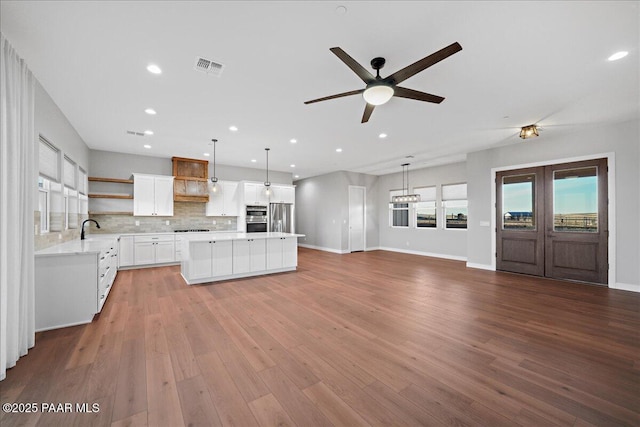 kitchen featuring stainless steel appliances, decorative backsplash, white cabinets, and hanging light fixtures