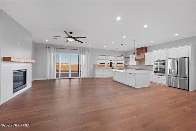 kitchen featuring a center island, white cabinets, hanging light fixtures, a brick fireplace, and stainless steel appliances