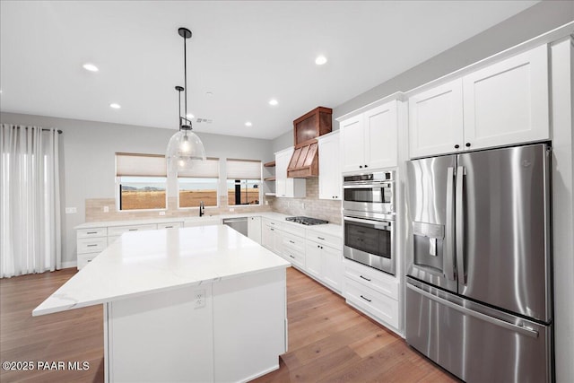 kitchen with pendant lighting, a center island, white cabinets, and stainless steel appliances