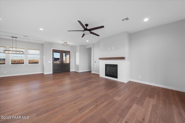 unfurnished living room with ceiling fan, a fireplace, and wood-type flooring