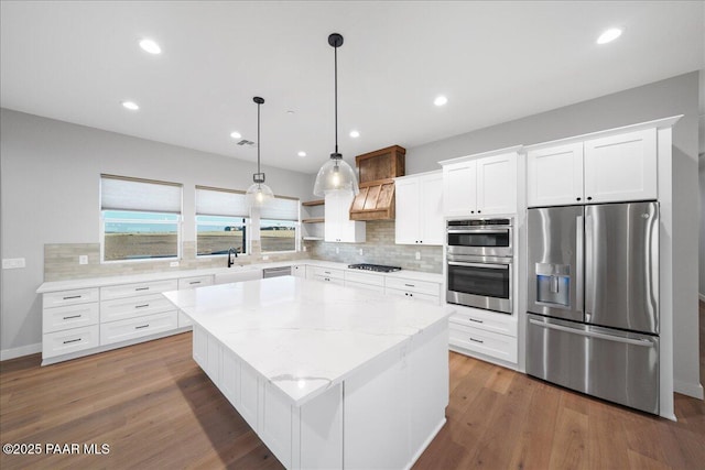 kitchen featuring white cabinetry, a center island, stainless steel appliances, decorative light fixtures, and decorative backsplash