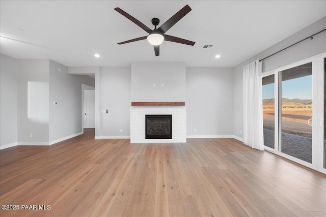 unfurnished living room featuring ceiling fan, a fireplace, and light hardwood / wood-style flooring