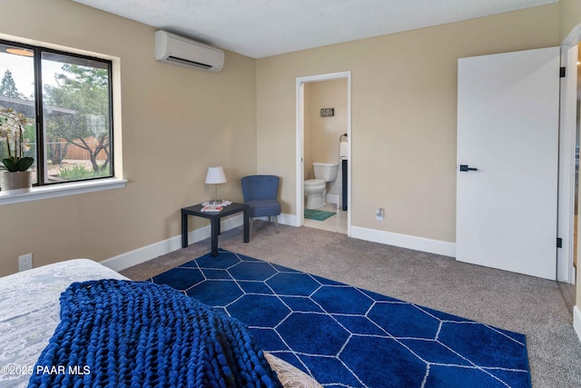 carpeted bedroom featuring a wall mounted air conditioner, a textured ceiling, and ensuite bath