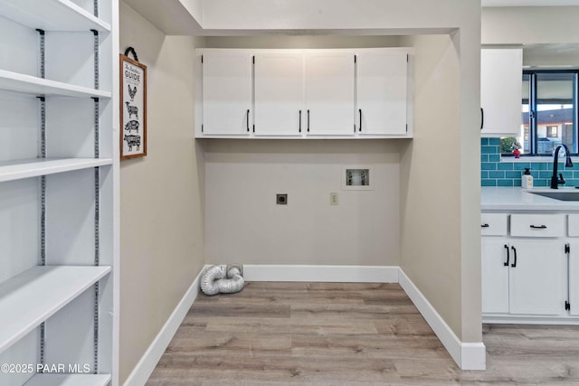 laundry room featuring sink, hookup for a washing machine, cabinets, light hardwood / wood-style floors, and hookup for an electric dryer