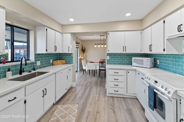 kitchen with sink, white cabinetry, tasteful backsplash, light wood-type flooring, and white appliances