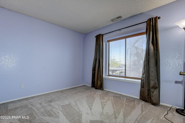 carpeted spare room with baseboards, visible vents, and a textured ceiling