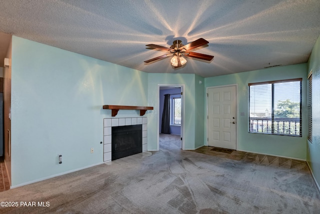 unfurnished living room featuring a ceiling fan, carpet flooring, a textured ceiling, and a fireplace