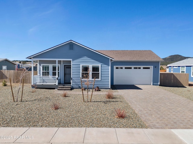 view of front of property with decorative driveway, an attached garage, and fence