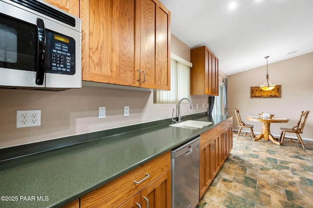 2770 Ridge Rd, Prescott, AZ 86301 - kitchen featuring appliances with stainless steel finishes, stone finish floors, dark countertops, brown cabinetry, and decorative light fixtures