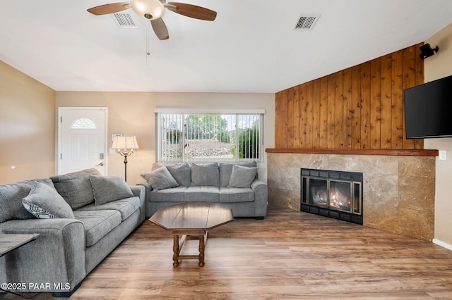2770 Ridge Rd, Prescott, AZ 86301 - living room with light wood-style flooring, ceiling fan, a tiled fireplace, and wooden walls