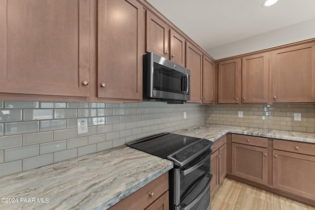 kitchen with decorative backsplash, light stone counters, and appliances with stainless steel finishes