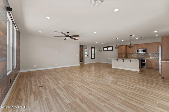 unfurnished living room featuring ceiling fan and light hardwood / wood-style flooring