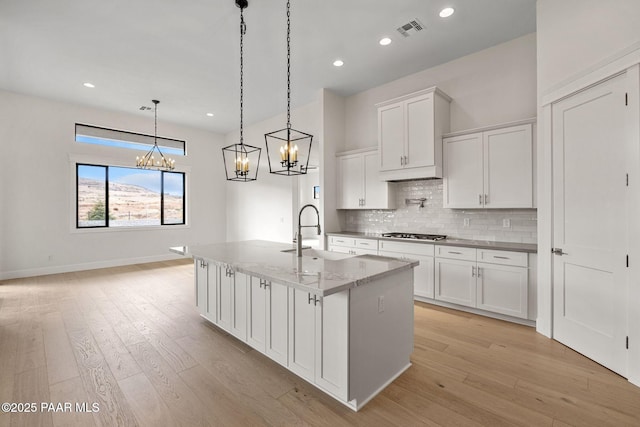 4655 E Alma Ln, Prescott Valley, AZ 86314 - kitchen featuring a chandelier, tasteful backsplash, white cabinetry, an island with sink, and light wood-style flooring