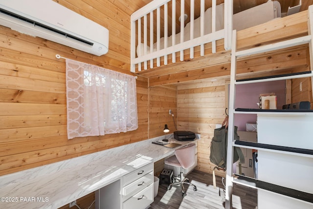 office area with built in study area, wooden walls, a wall mounted air conditioner, and wood finished floors