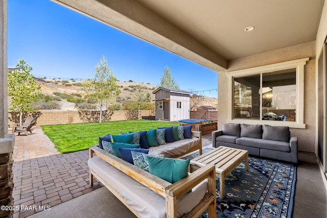 view of patio / terrace featuring an outdoor living space, a fenced backyard, an outbuilding, and a storage unit