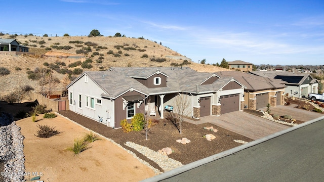 traditional-style house with fence, an attached garage, driveway, and stone siding