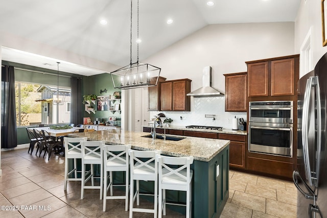 kitchen with an inviting chandelier, decorative backsplash, light stone countertops, wall chimney exhaust hood, and a sink