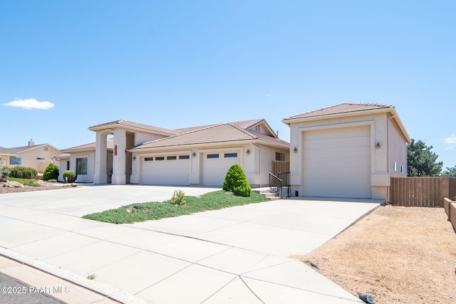 view of front of property with stucco siding, driveway, an attached garage, and fence