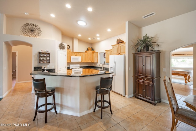 kitchen featuring arched walkways, visible vents, white appliances, and a sink