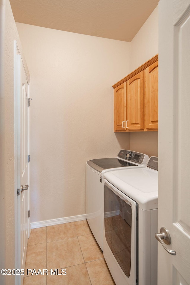 washroom with washer and dryer, light tile patterned floors, cabinet space, and baseboards