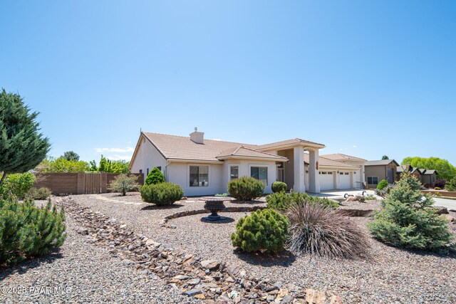 view of front of house featuring stucco siding, fence, a garage, a chimney, and a tiled roof